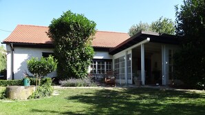 A house with a tiled roof, a covered patio, and a well-maintained lawn. - house DEV (Maribor)