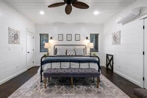 A bedroom with a bed, two bedside lamps, a ceiling fan, and a bench. - Oklahoma Sky (Broken Bow)