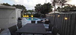 A backyard with a swimming pool, patio furniture, and a wooden fence.