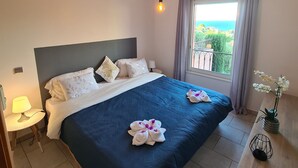 Hotelkamer met een bed, nachtkastje met lamp, raam met gordijnen en uitzicht op de omgeving.