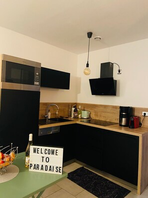 A modern kitchen with a microwave, toaster, coffee maker, and a welcome sign. - Apparemment pour 4 personnes (Lumio)