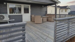 Une terrasse extérieure couverte, équipée d’une table et de chaises, d’une fenêtre et d’un ventilateur.