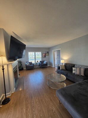 Ein Wohnzimmer mit Flachbildfernseher, zwei Sofas, einem Couchtisch und einem Kamin.