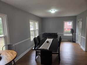 Ein Esszimmer mit einem langen Tisch, Stühlen und einem Ventilator.