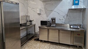 A kitchen with a stainless steel refrigerator, microwave, coffee machine, and a digital scale. - PALOMERAS Coliving & Coworking (Madrid)