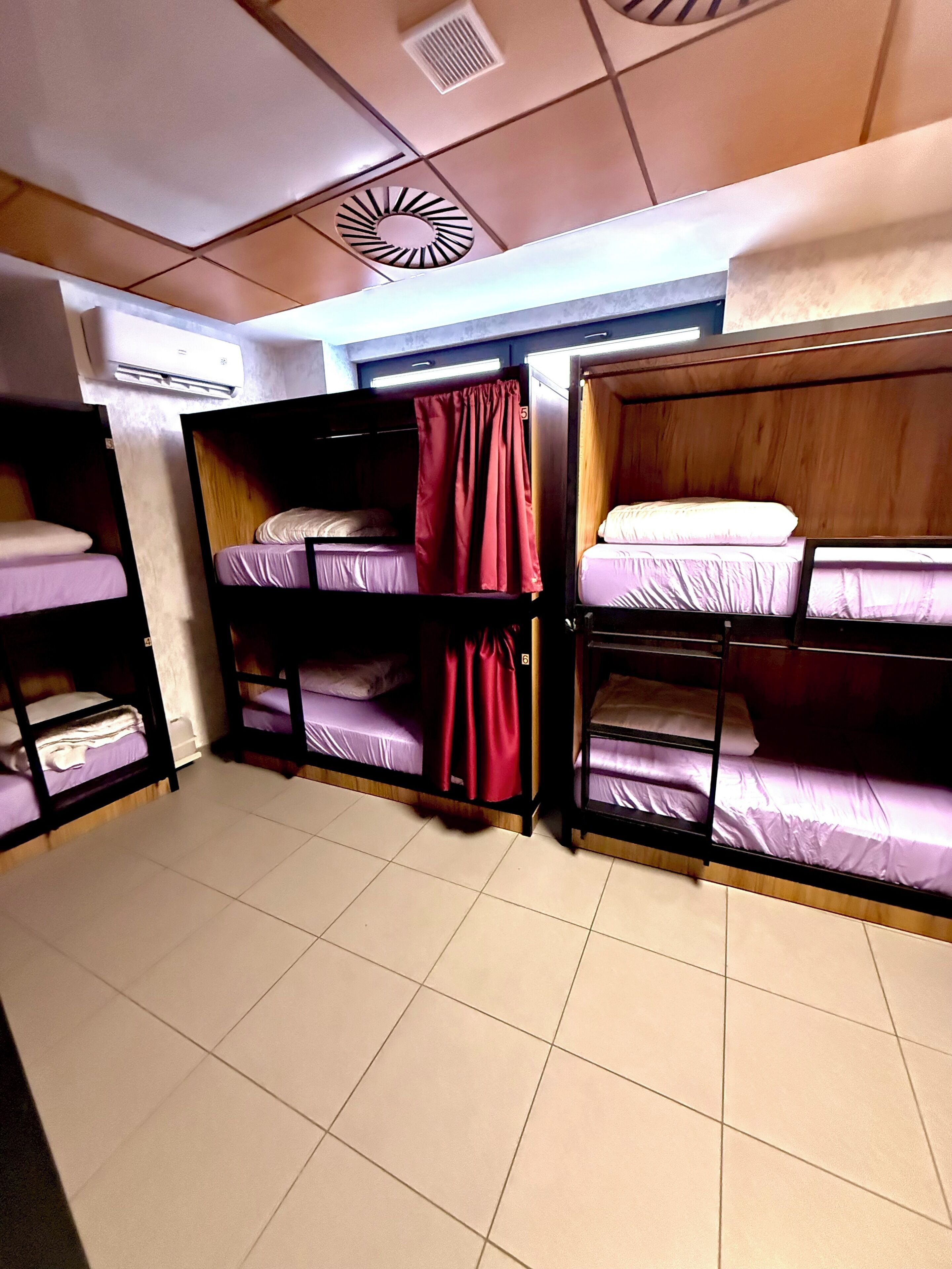 Ein Schlafsaalzimmer mit Etagenbetten, einem Deckenventilator und einer Wandklimaanlage.