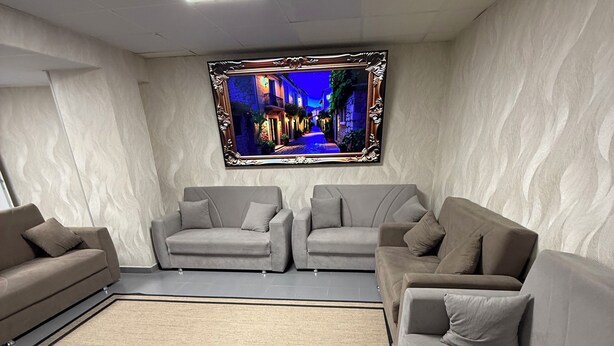 A modern living room with a flat-screen TV mounted on the wall, two sofas, a coffee table, and a patterned rug. - PALOMERAS Coliving & Coworking (Madrid)