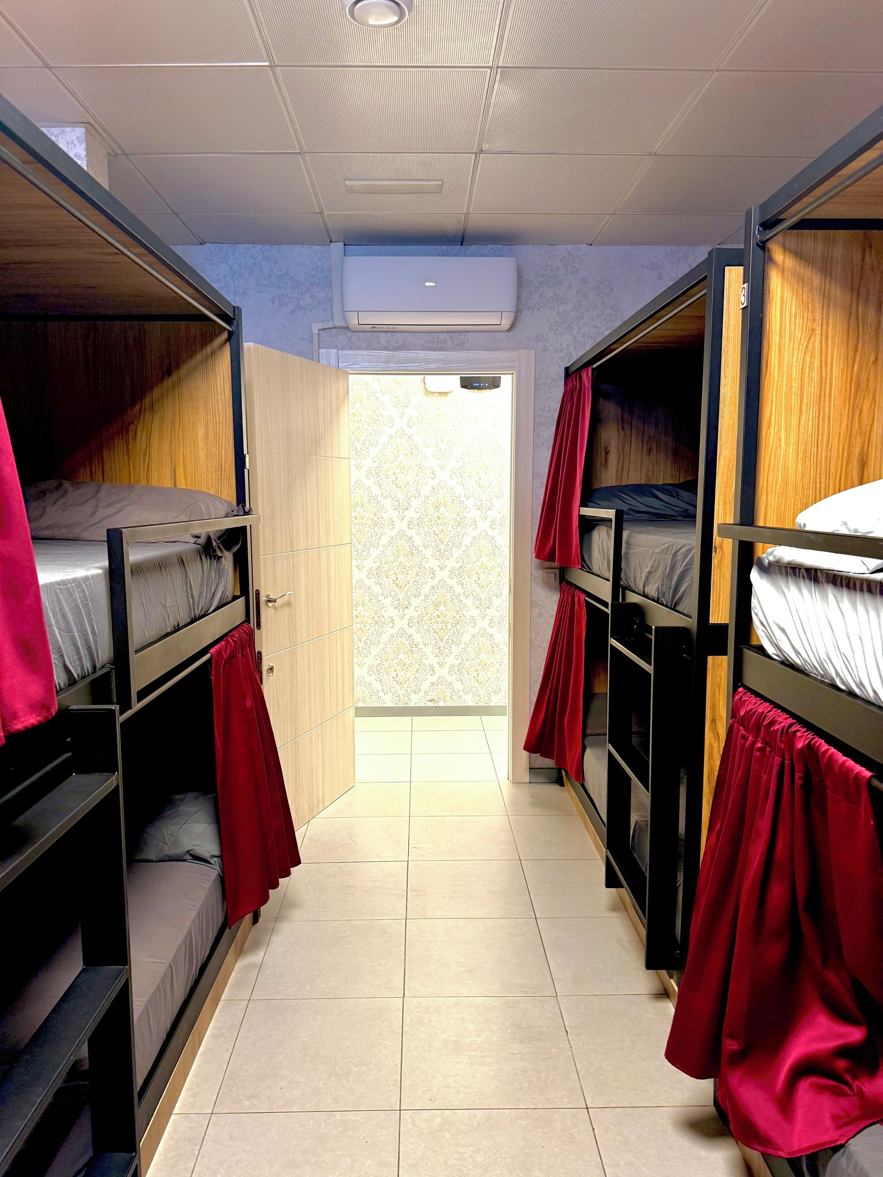 Un dormitorio con literas, suelo de baldosas y una ventana con cortinas.