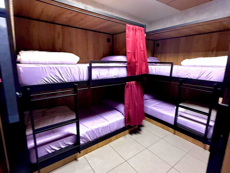 A bunk bed room with wooden walls, a tiled floor, and a red curtain.