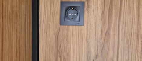 A wooden panel wall with a black metal frame and a square electrical outlet.