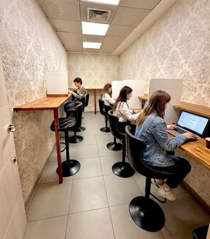 A salon with multiple barbers at work, each with a customer seated in a black chair. - PALOMERAS Coliving & Coworking (Madrid)
