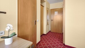 A hotel hallway with wooden doors, a red patterned carpet, and a potted orchid on a table. - XZLLENZ light TV Parking Elevator DZ TWIN Breakfast (Oberasbach)