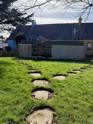 A grassy area with circular patterns, a building with a blue door, and a chimney.