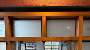 Ein Zimmer mit Holztisch, Fenster und Blick ins Freie.