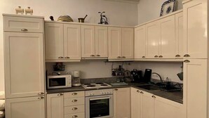 Eine kleine Küche mit weißen Schränken, einer Mikrowelle, einem Herd, einem Backofen und einer Spüle.