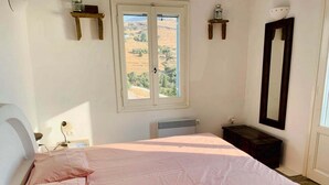 Ein Schlafzimmer mit Bett, Fenster, Heizkörper, Spiegel und einem kleinen Tisch.
