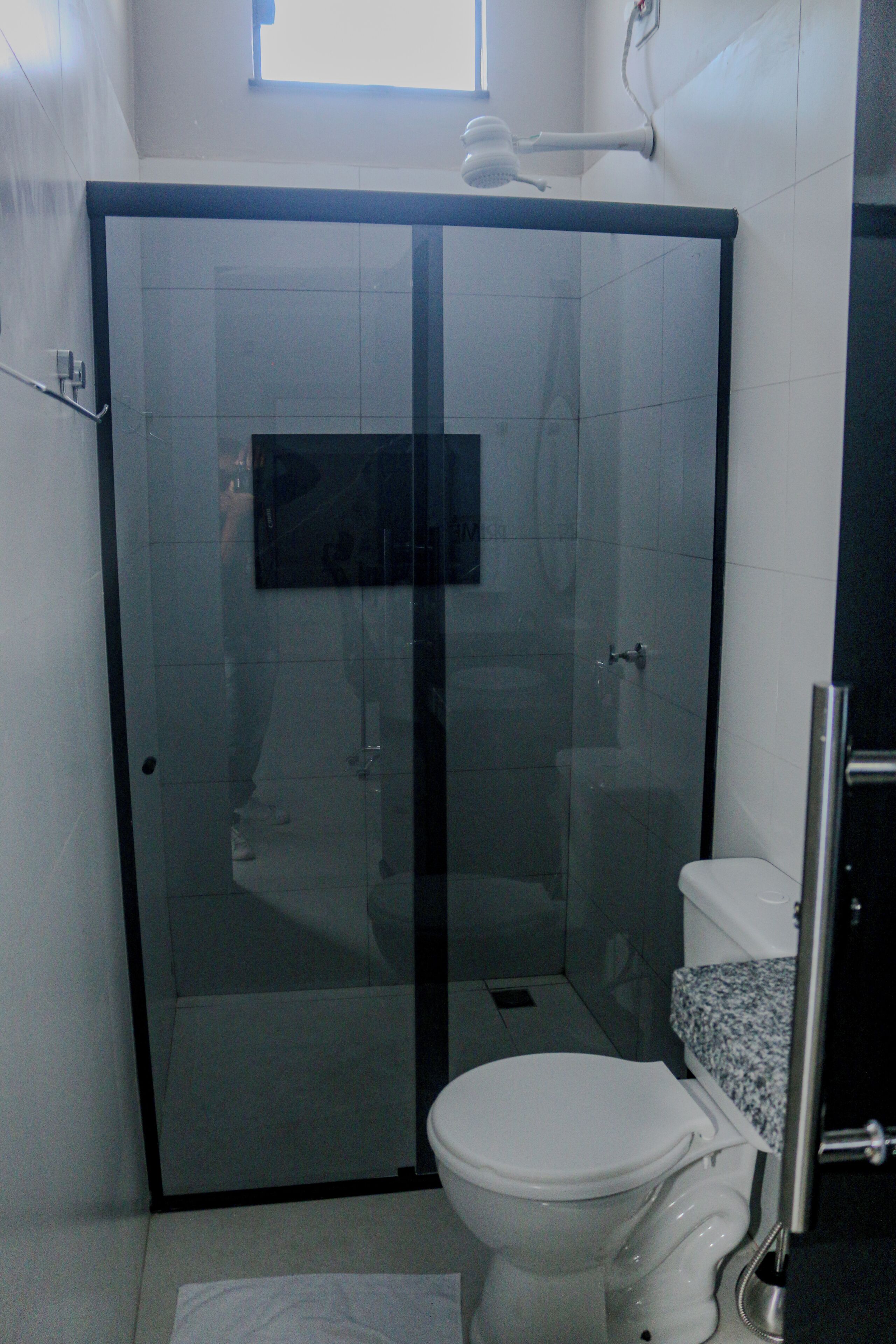 A bathroom with a glass-enclosed shower, a toilet, and a sink with a granite countertop.