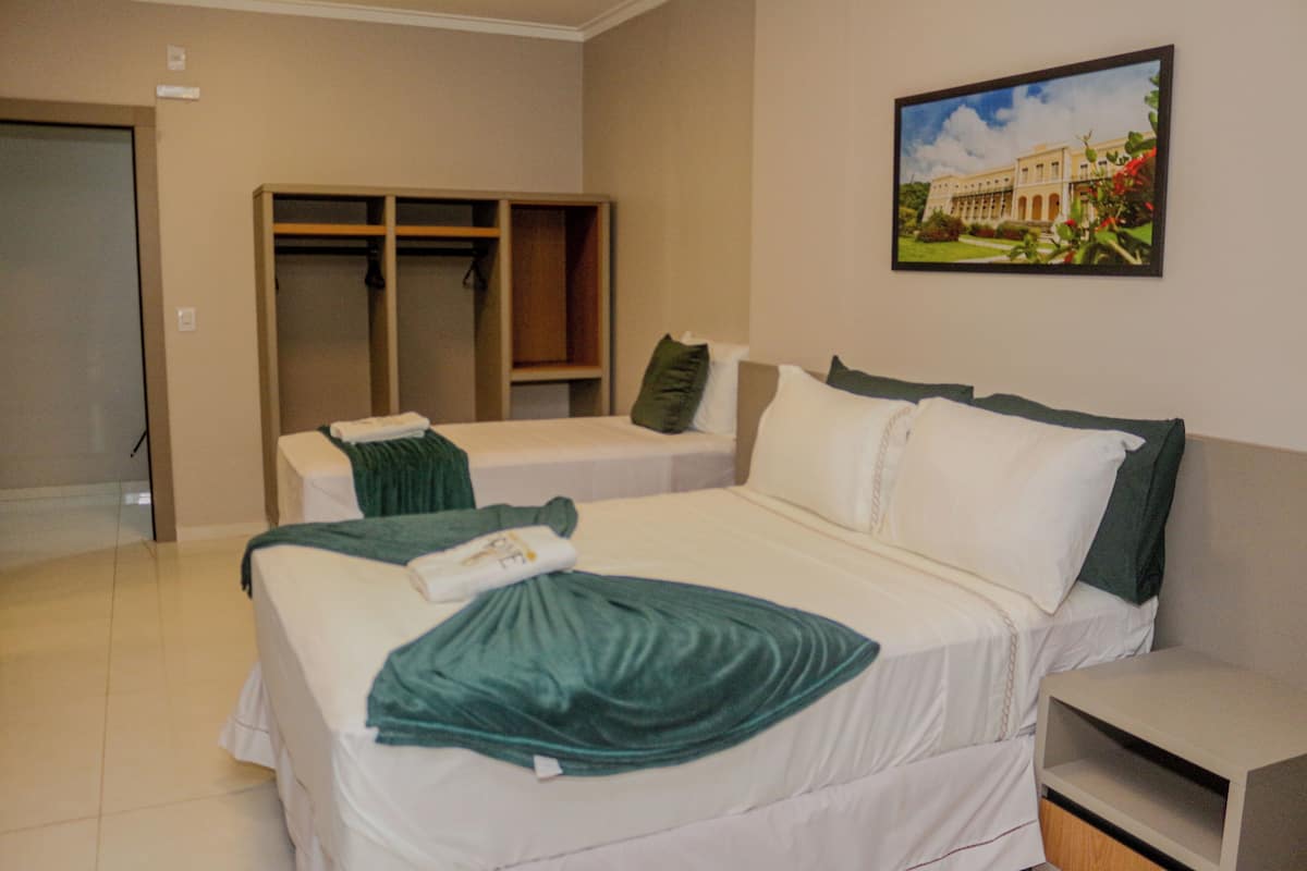 A hotel room with a bed, a bedside table, a wardrobe, and a painting on the wall.