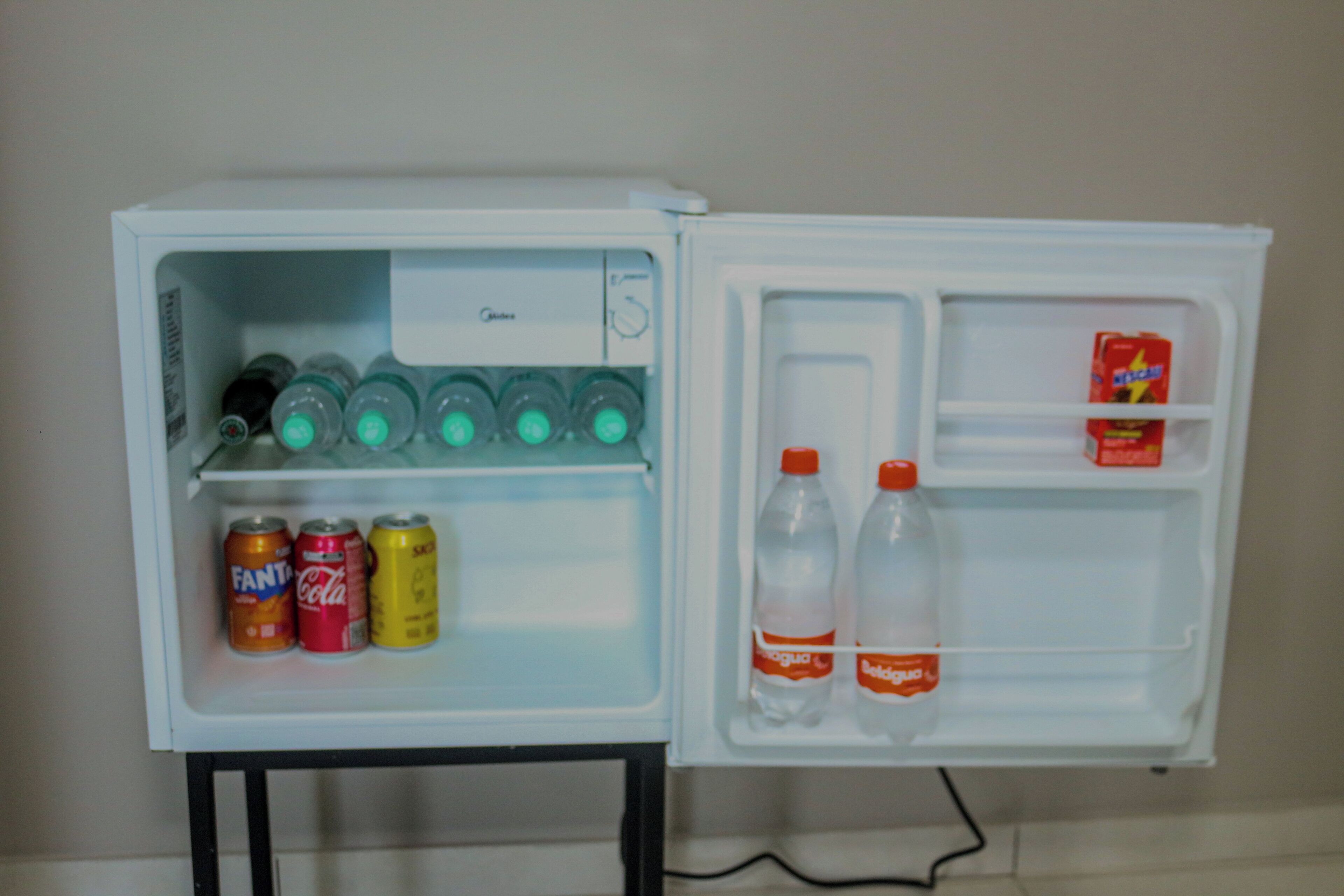 A small refrigerator with a freezer compartment, containing beverages and a carton of milk.