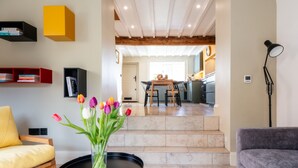 Una sala de estar moderna con una mesa de centro, un sofá, una zona de comedor con mesa y sillas, y una cocina al fondo.