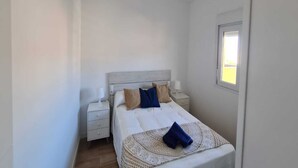 Un dormitorio con cama, mesita de noche y ventilador de techo, además de una ventana.