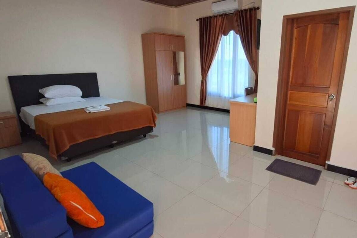 A hotel room with a bed, a desk, a wardrobe, and a bathroom.