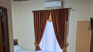A hotel room with two beds, a wooden wardrobe, a door, and a ceiling-mounted air conditioner. - ACO BORNEO HOTEL (Malinau)