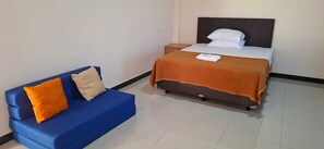 Una habitación con una cama, un sofá azul y una mesita de noche.
