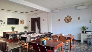 A conference room with tables, chairs, a TV, and decorative plates on the wall. - ACO BORNEO HOTEL (Malinau)