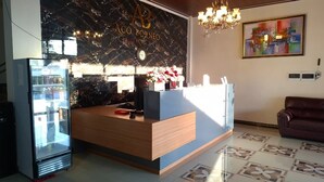 A hotel reception desk with a marble wall, a clock, and a chandelier. - ACO BORNEO HOTEL (Malinau)