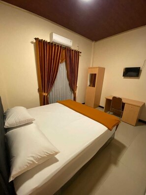 A room with a bed, a desk, a wardrobe, and an air conditioning unit. - ACO BORNEO HOTEL (Malinau)