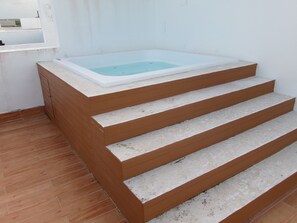 A bathroom with a bathtub, wooden steps, and a tiled floor. - Tranquil apartment with AC in vibrant Bavaro perfect for relaxing (bavaro)