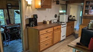 A kitchen with wooden cabinets, a stove, a coffee maker, and a window.