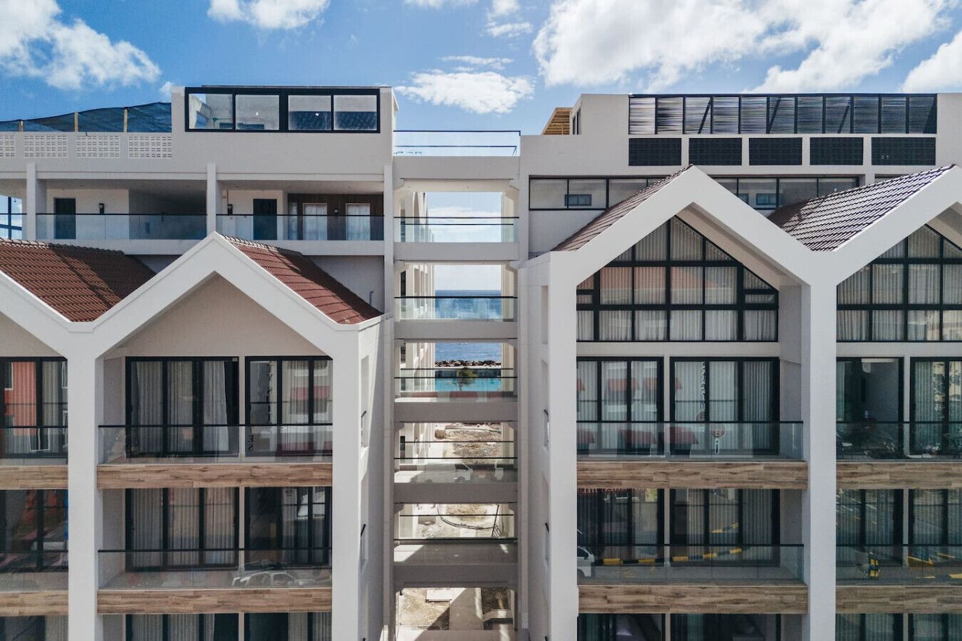 Un edificio moderno de varios pisos con balcones, ventanas amplias y una vista despejada del mar.
