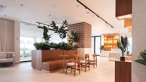 Ein modernes Interieur mit einer Sitzecke, einem hölzernen Raumteiler mit Pflanzen und einem hellen, gut beleuchteten Raum.