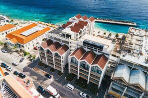 A multi-story hotel with a parking lot, a pool, and a view of the ocean. - Majestic 2-Bed Pool Access Ocean View by Bocobay (Willemstad)