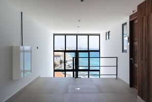 A hallway with a large window, a door, and a wall-mounted light fixture. - Majestic 2-Bed Pool Access Ocean View by Bocobay (Willemstad)