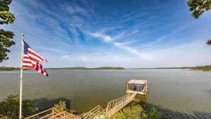 Eine Pier, die in einen ruhigen See ragt, mit einer US-amerikanischen Flagge, umgeben von Grünpflanzen und blauem Himmel.