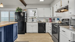 Eine moderne Küche mit weißen Schränken, einem schwarzen Kühlschrank, einem Herd und einem Geschirrspüler.