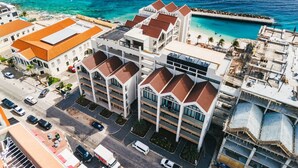 A multi-story hotel with a parking lot, a pool, and a view of the ocean. - Majestic 2-Bed Pool Access Suite by Bocobay (Willemstad)