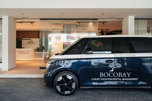 A luxury car parked in front of a building with a sign reading 'BOCOBAY LUXURY VACATION RENTAL MANAGEMENT.' - Majestic 2-Bed Pool Access Suite by Bocobay (Willemstad)