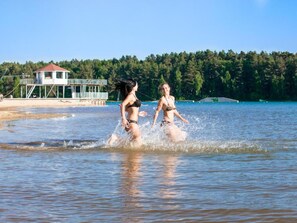 Dos personas en una piscina, con un edificio y árboles al fondo.