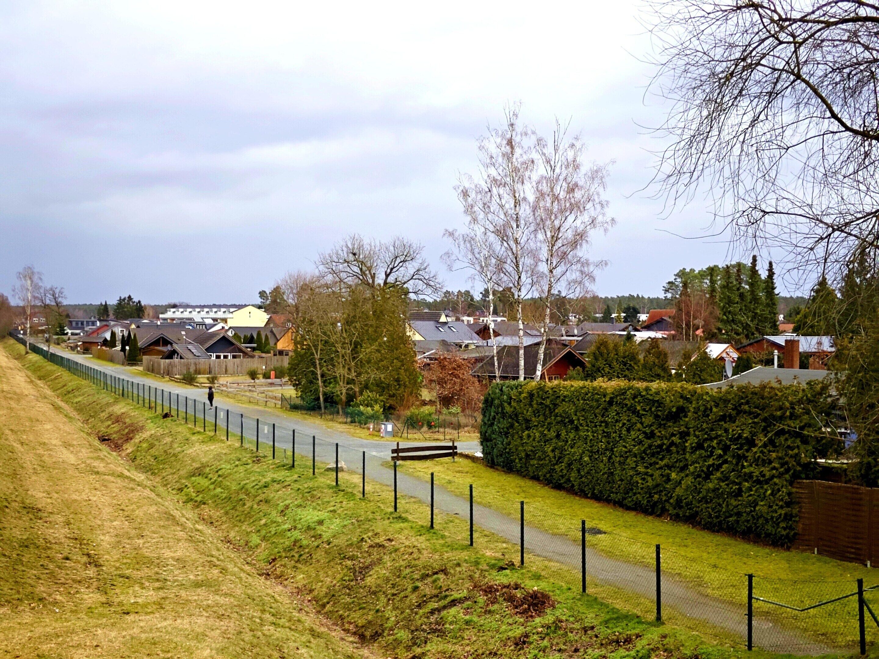 Un quartier résidentiel avec des maisons, un sentier délimité par une clôture et un banc.
