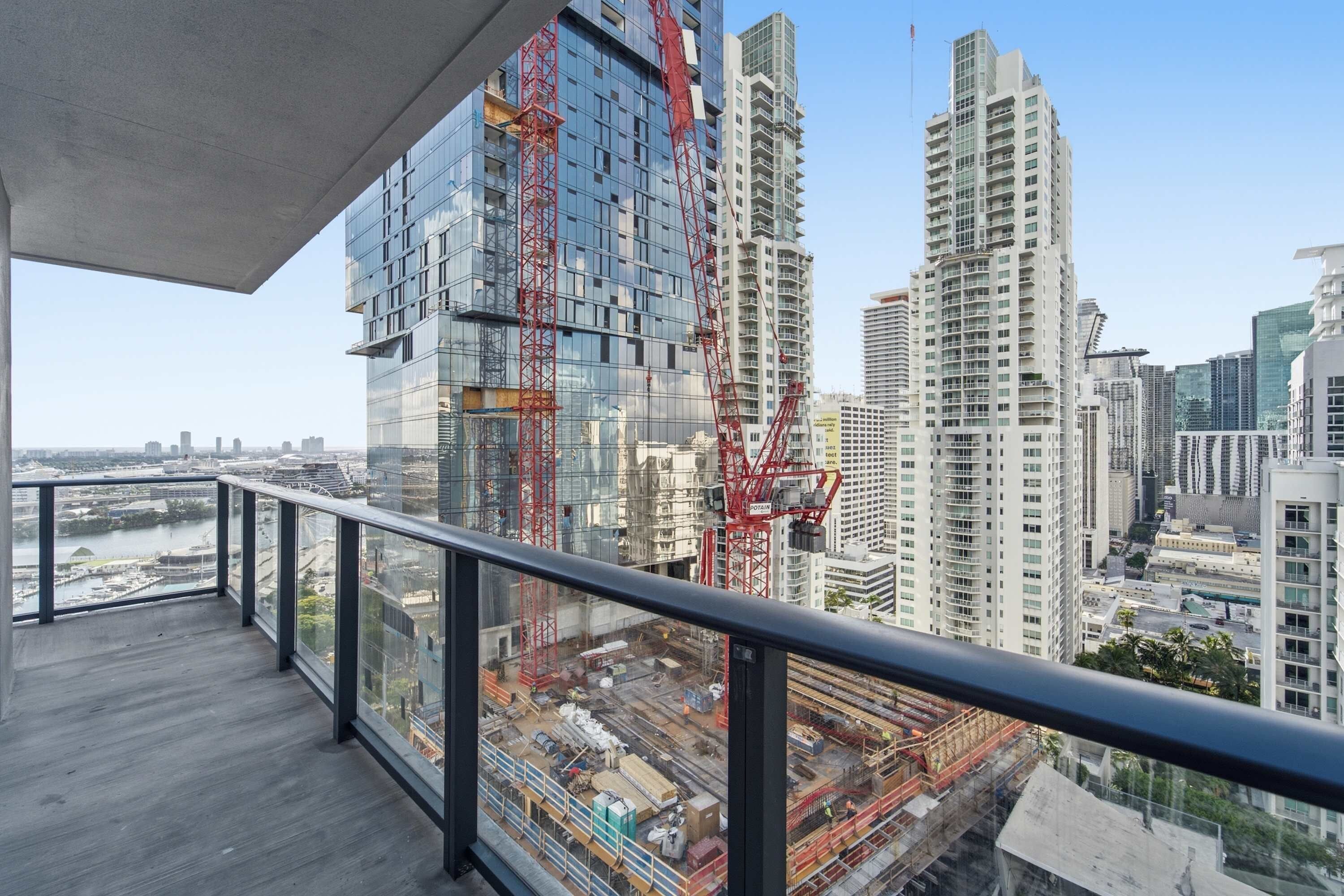 A high-rise building with a modern glass facade and a construction crane.