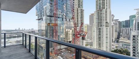 A high-rise building with a modern glass facade and a construction crane.