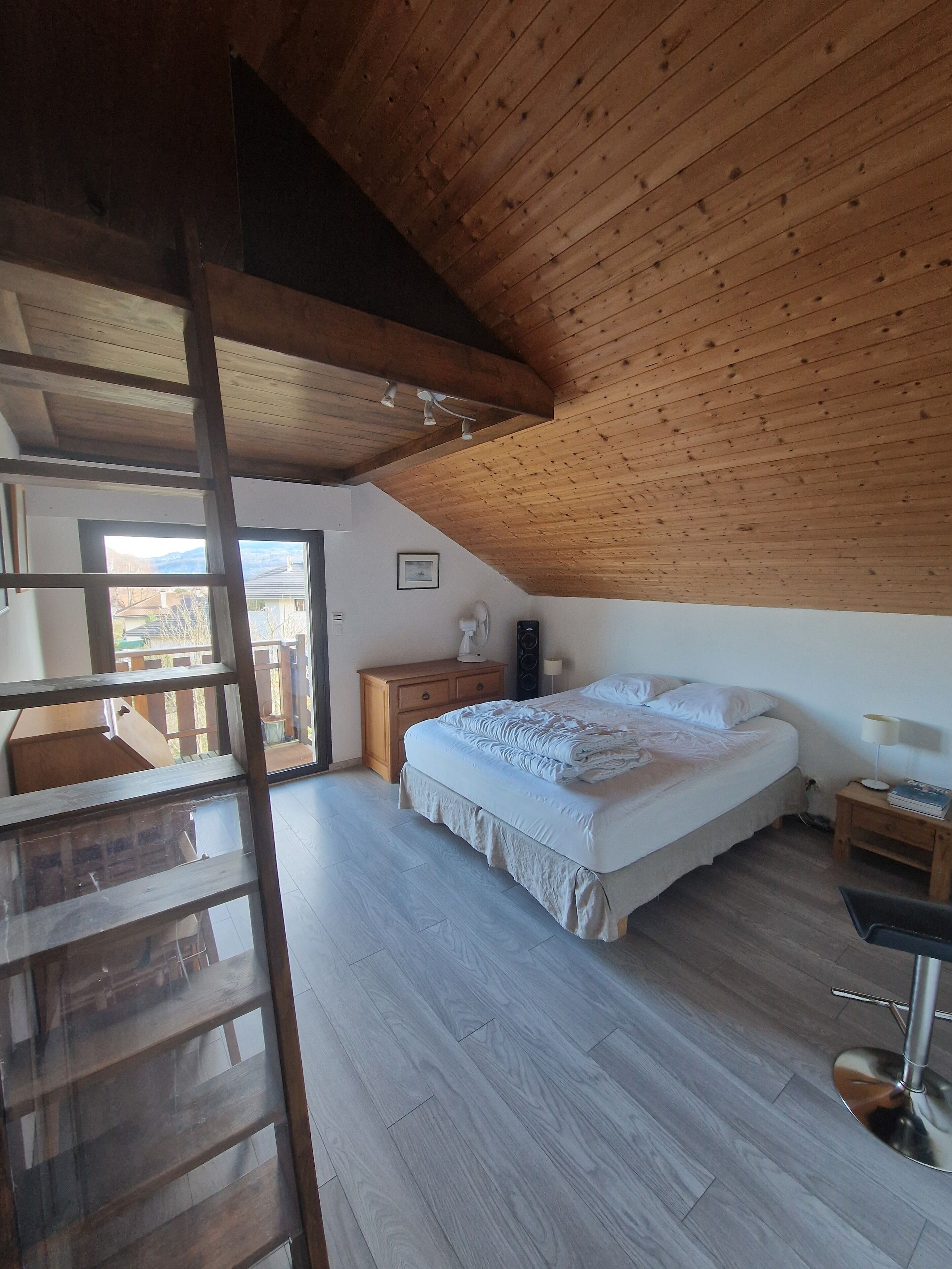 Une chambre à coucher avec un plafond en bois, un lit, une table de chevet, un bureau et une chaise.