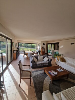 A spacious living area with a sofa, coffee table, and chairs, large windows, and a view of the outdoors. - Family home ideal for 3 families (sleeps 14) (Saint-Jorioz)