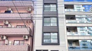 Ein mehrstöckiges Gebäude mit moderner Fassade, Klimaanlagen und einem sichtbaren Eingang.