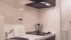 Une cuisine moderne équipée d’un lave-vaisselle intégré, d’un évier en acier inoxydable et d’une hotte noire.