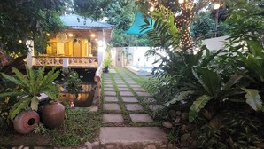 A garden pathway leading to a building with a covered porch, surrounded by lush greenery and potted plants. - Private Pool Villa in Bataan
Casa Lily Tropical Staycation Near Manila (Hermosa)
